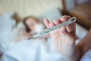 UKAS Accreditation Hand holding a thermometer at home